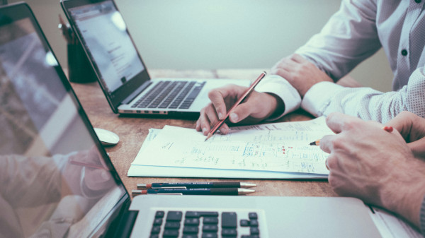 Zwei Herren konzepieren eine PIM Auswahl auf einem Zettel