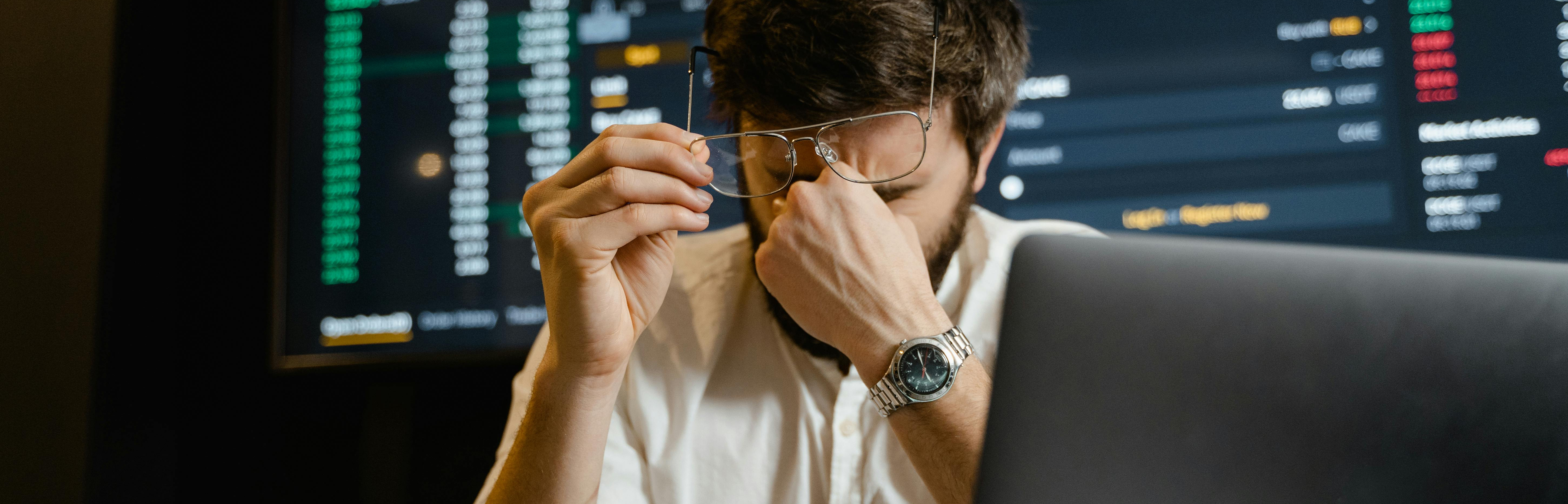 Analyst vor seinem Laptop. Im Hintergrund großer Screen mit verschiedenen Daten