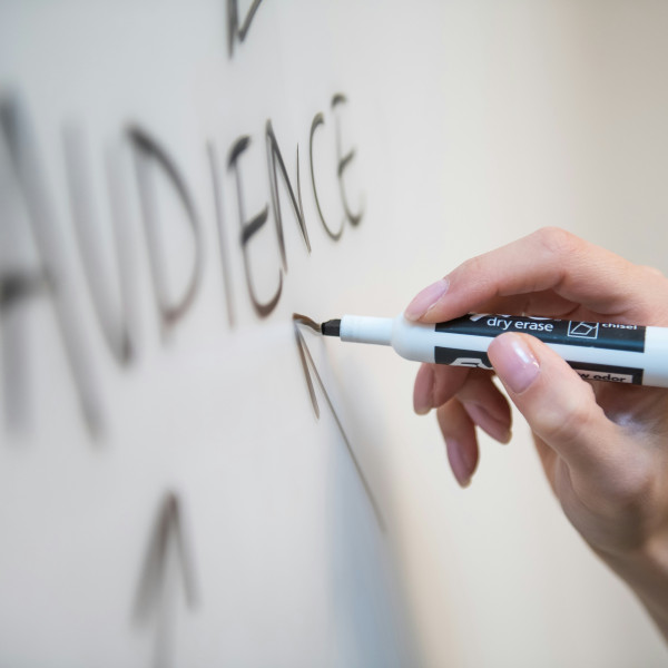 Hand zeichnet einen Pfeil in Richtung auf das Wort Audience auf einem White Board