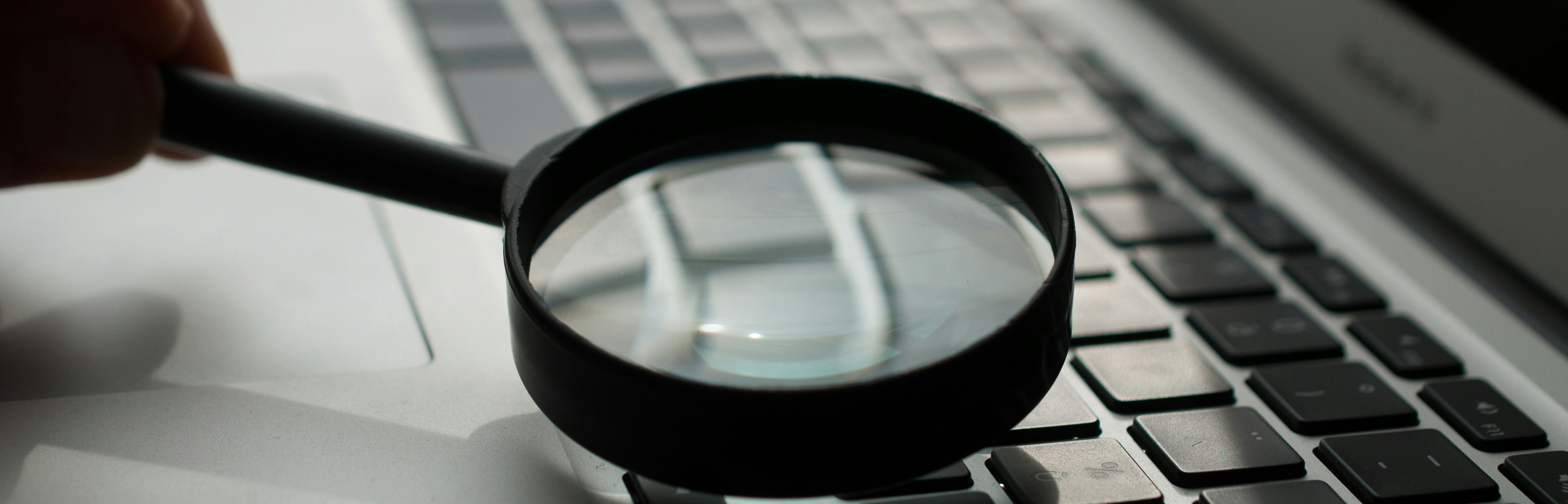 Lupe über einem Laptop. Sinnbild für Prüfung der digitalen Barrierefreiheit