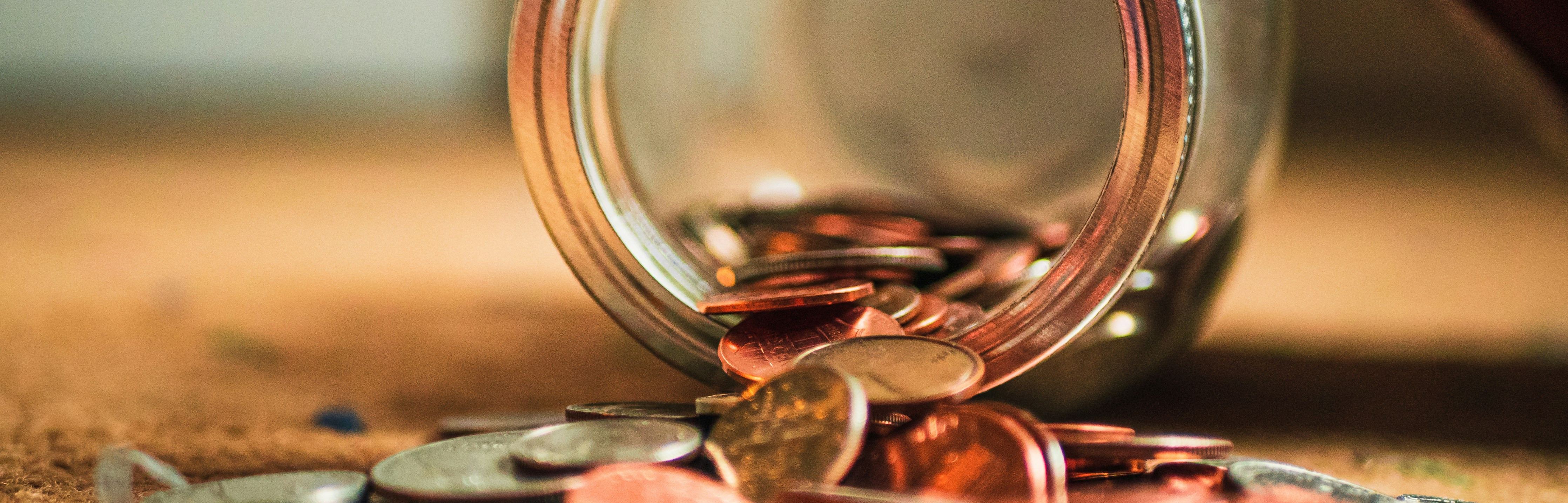 Ein Haufen Münzen vor einer ausgeschütteten Spardose