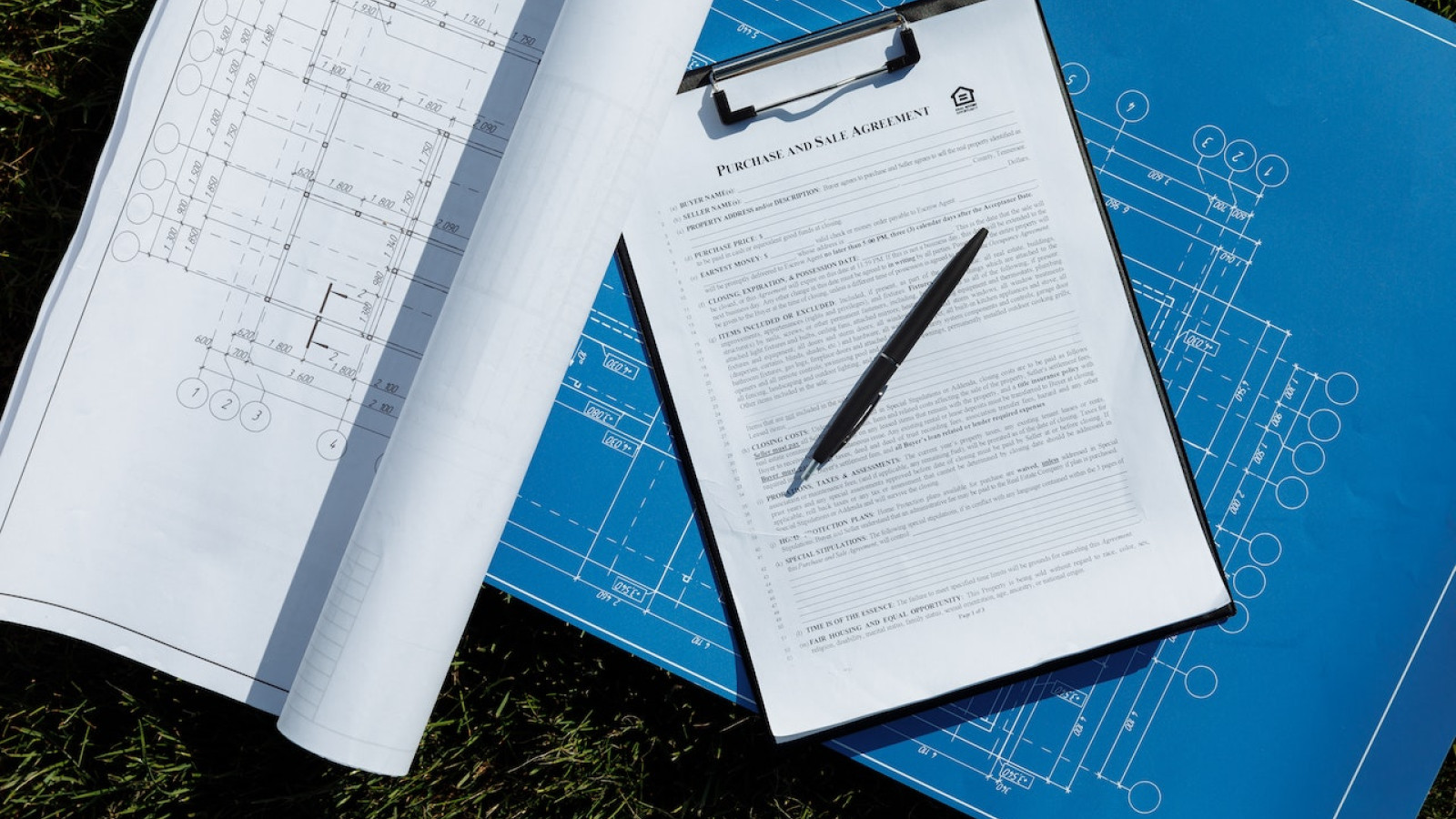 blaupausen-und-ein-stift-auf-dem-gras.