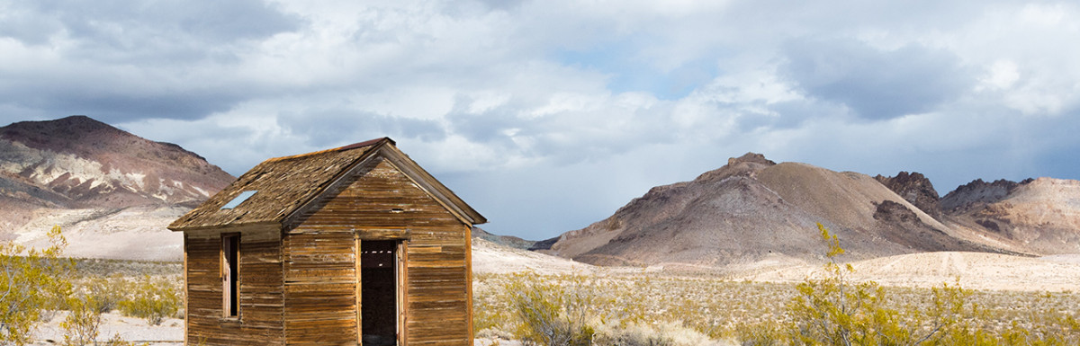 Eine verlassene Holzhütte in einer kargen Wüstenlandschaft