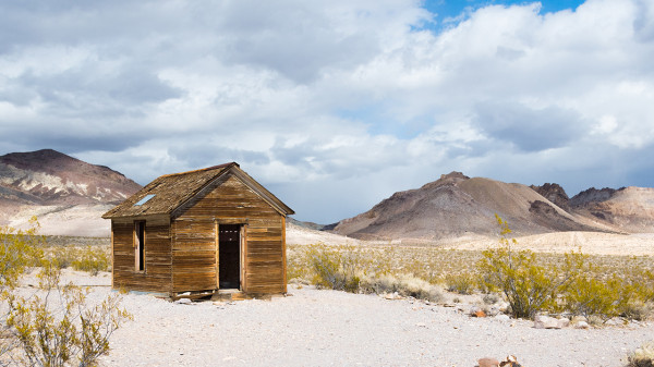 Eine verlassene Holzhütte in einer kargen Wüstenlandschaft